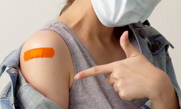 Woman-Pointing-Finger-at-Bandage-on-her-arm-After-Getting-Vaccinated